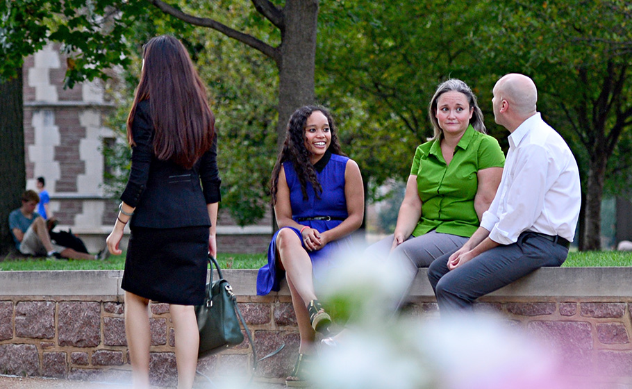 faculty and student sitting & conversing outdoors