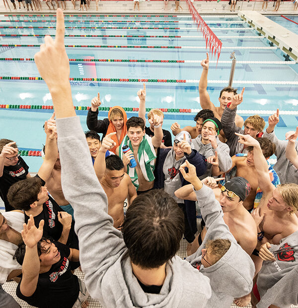 WashU swim team huddling before meet by a pool