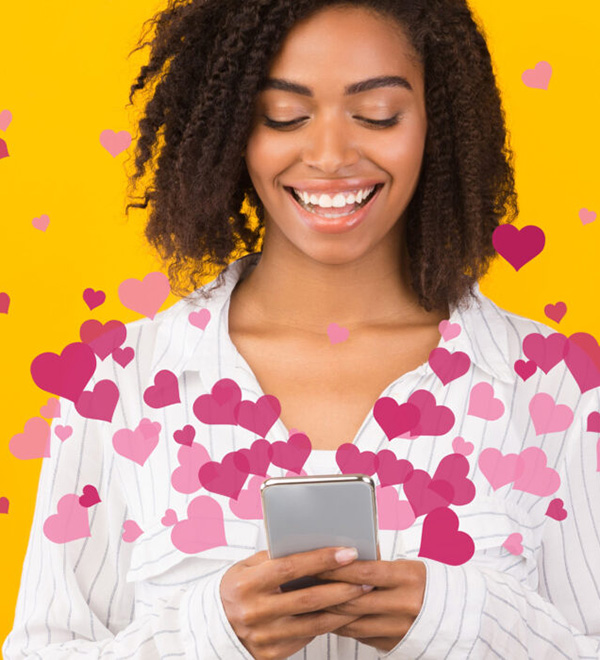 African American woman looking at phonr on yellow background with heart illustrations